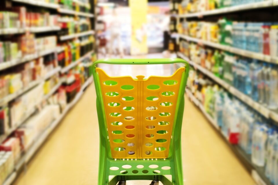 Yellow,plastic,shopping,cart,among,rows,of,products,in,a